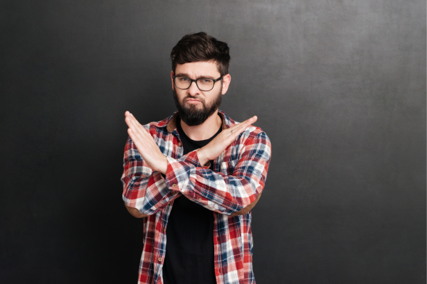 nein-sagen-lernen-selbstbestimmt-nein-sagen Ein Mann kreuzt seine arme weil er es satt hat, ständig Ja zu sagen.